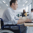 Disabled man sits in a wheelchair and works in an office on a laptop - Краевое профобъединение