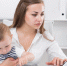 Serious woman with child is сoncentratedly working behind laptop - Краевое профобъединение