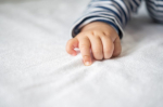 Newborn baby hand in white bed. Selective focus.